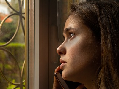 Image of woman standing at a window, talking on the phone - © Adobe Stock/#334725111