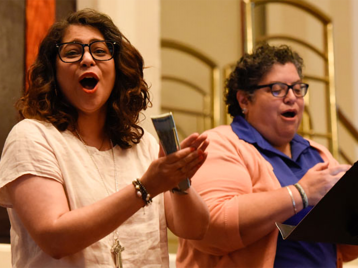 General Assembly Co-Moderator and Ruling Elder Vilmarie Cintrón-Olivieri joins Marissa Galvan-Valle to help lead the Big Tent plenary in singing Thursday. (Photo by Rich Copley)