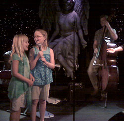 Photo of two young girls singing on stage 