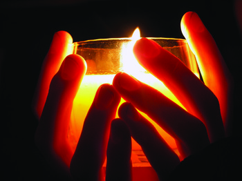 Hands holding a candle in the darkness