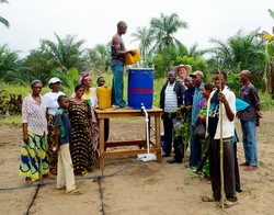 Following the installation of the drip irrigation system for the women’s farming group near Kananga, everyone gathers for a photo as the drum is filled with water.