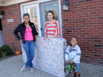 Jessica Collins, left, and a friend deliver a mattress to a boy who didn’t have one.