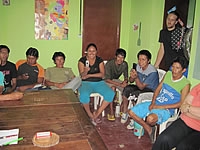 A group of people sitting around a wooden table in a green-painted room.