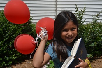 young girl holding balloons and Presbyterian hymnal