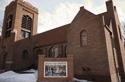 The entrance of a large, brown brick church.