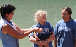 A toddler is baptized in a river.