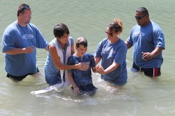 A boy is baptized by several people.