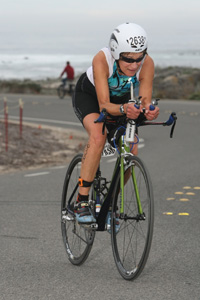 A woman in running gear, cycling on a bike.
