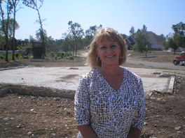 A woman stands on an empty lot, where her home once stood.
