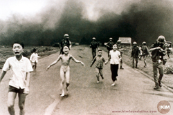 Black and white photo of people running from a napalm fire.