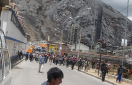 A crowd standing near a building in front of a large mountain, after an attack.