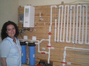 The Rev. Leticia Ramos, pastor of Prince of Peace Presbyterian Church, with the water system installed by Living Waters for the World.