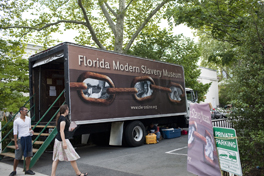 People walking from a large truck with the words "Florida Workers Slavery Museum"