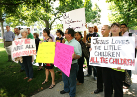 A group of people holding signs outside of a building for a demonstration.