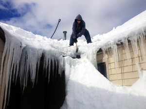 Workers try to remove heavy snow from the roof of the First Presbyterian Church in Worcester, Mass.