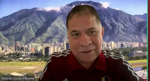 A man speaking on screen with mountains in the background