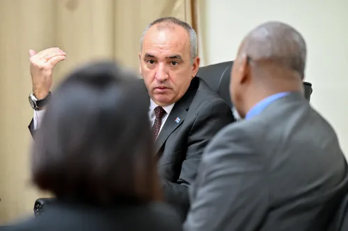 A man speaks to two people whose heads are shown from behind.