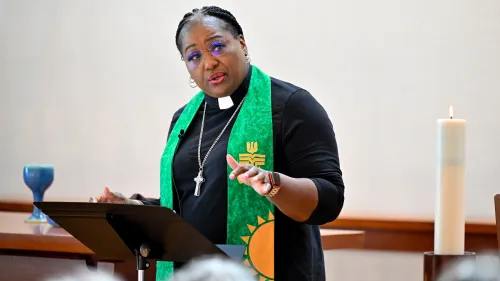 A woman speaks at the pulpit of a chapel.
