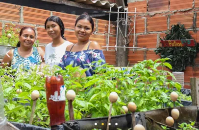 Three women smiling behind vegetables