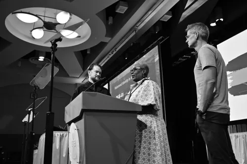 The Racial Justice Committee moderator Patricia Bligen Jones (center) and vice-moderator Steve Watts (right) work with Jared Michael Brown (left) during plenary rehearsal on June 28. Photo by Rich Copley.