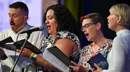 four people singing out of hymns at GA227 Monday, June 29, 2026