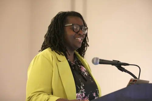 Natarsha Sanders stands  behind podium speaking at the women of faith breakfast GA227