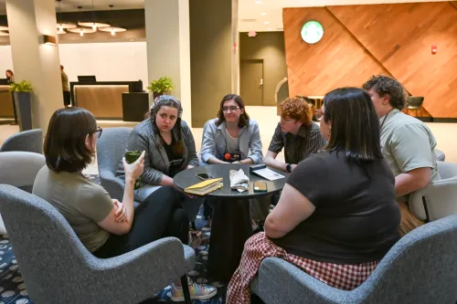 people seated around table listening to one person talk
