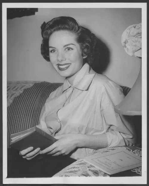 21 year old Colleen Townsend sits on a couch in her home, with a copy of the New Testament in hand. She smiles at the camera.
