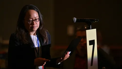Rev. Jihyun Oh, Stated Clerk of the General Assembly & Executive Director of PL&W stands at the microphone in the role of corresponding member to offer clarity of the intent of a motion related to RIW-01 during the 9th plenary. Photo by Rich Copley. 