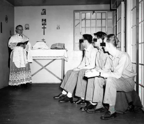 Four men sit on a bench at the right of the frame. They are death row inmates in Utah, photographed in 1952.