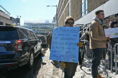 A man holds a sign quoting deuteronomy at a pro-immigrant faith vigil. 