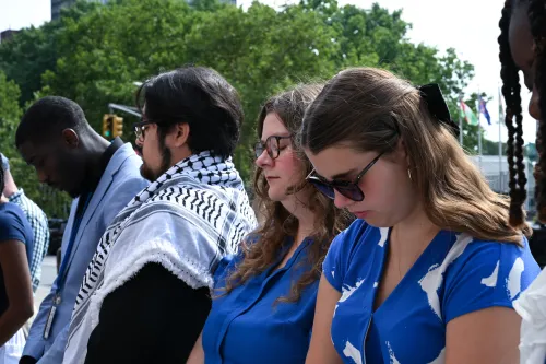 A GROUP OF YOUNG ADULTS IN PRAYER OUTDOORS