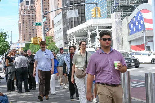 A group of young adults walk down a street in New York City.