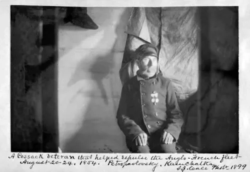 A man wearing an army uniform sits in a chair and looks out the window.