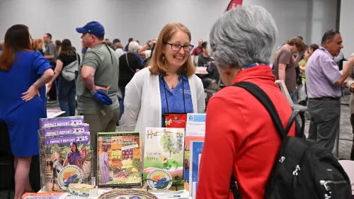 A woman with red hair smiles brightly while in a crowded room of people