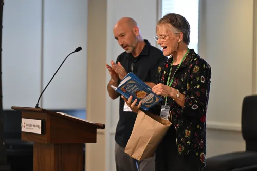 Bishop Budde delights in a cookbook based on the late Dolly Parton's recipes given as a gift from The Upper Room publishing division of the United Methodist Church, hosts for the 2026 AI & Church Summit.