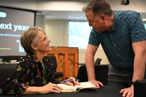 Bishop Mariann Budde signs copies of her book for AI & Church participants.