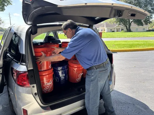 A man handling flood recovery buckets in the back of a van