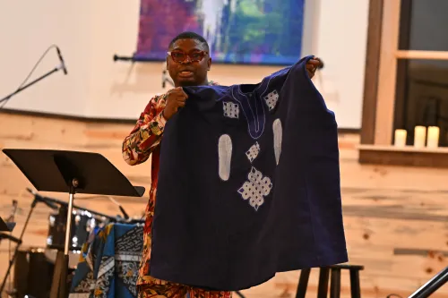 &nbsp;The Rev. Ebenezer Alonge holds up a handwoven Nigerian garment to illustrate how many distinct contributions can come together as one, like the church.