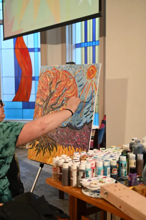 Lauren Christian finishes the painting of a fall tree aflame as opening worship closes for the Jesus and Justice Young Adult Advocacy Conference. 