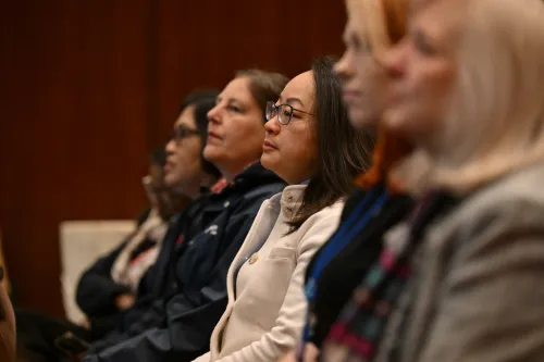 A row of women face to the left, seated and solemn, in a church setting