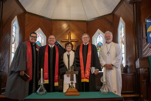 Ministers in a group photo inside a church with cross behind them and in front of them