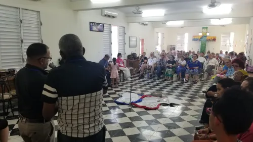 A large group of Cubans and US Americans sit and listen to a presentation in a seminary chapel.