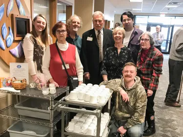 group of people standing in front of a cart of coffee cups