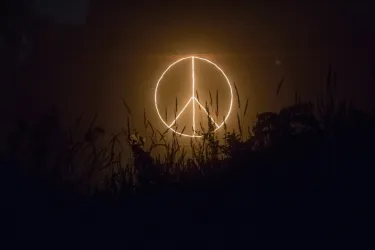 A neon peace sign glows in the dark