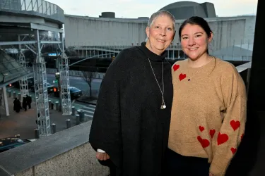 A mom and her adult daughter are all smiles while posing for a photo