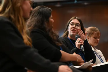 Woman with dark hair looks to the side as she says something during a panel discussion