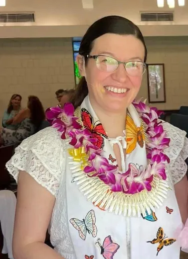 Woman with glasses and a scarf covered with butterflies smiles