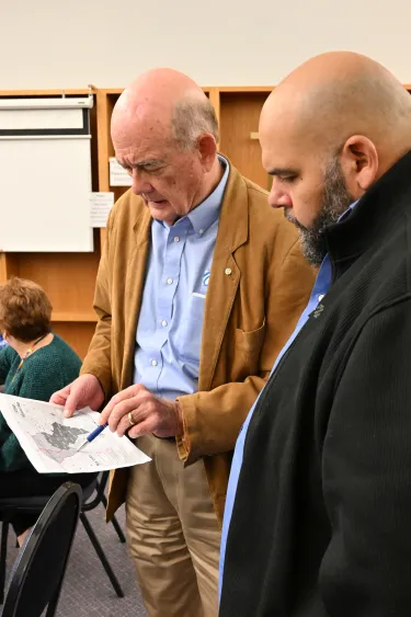Two men conferring while one holds a document or map