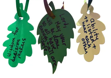 Three leaves, of varied colors, made of construction paper. Each has a hope, prayer, or wish written on it.